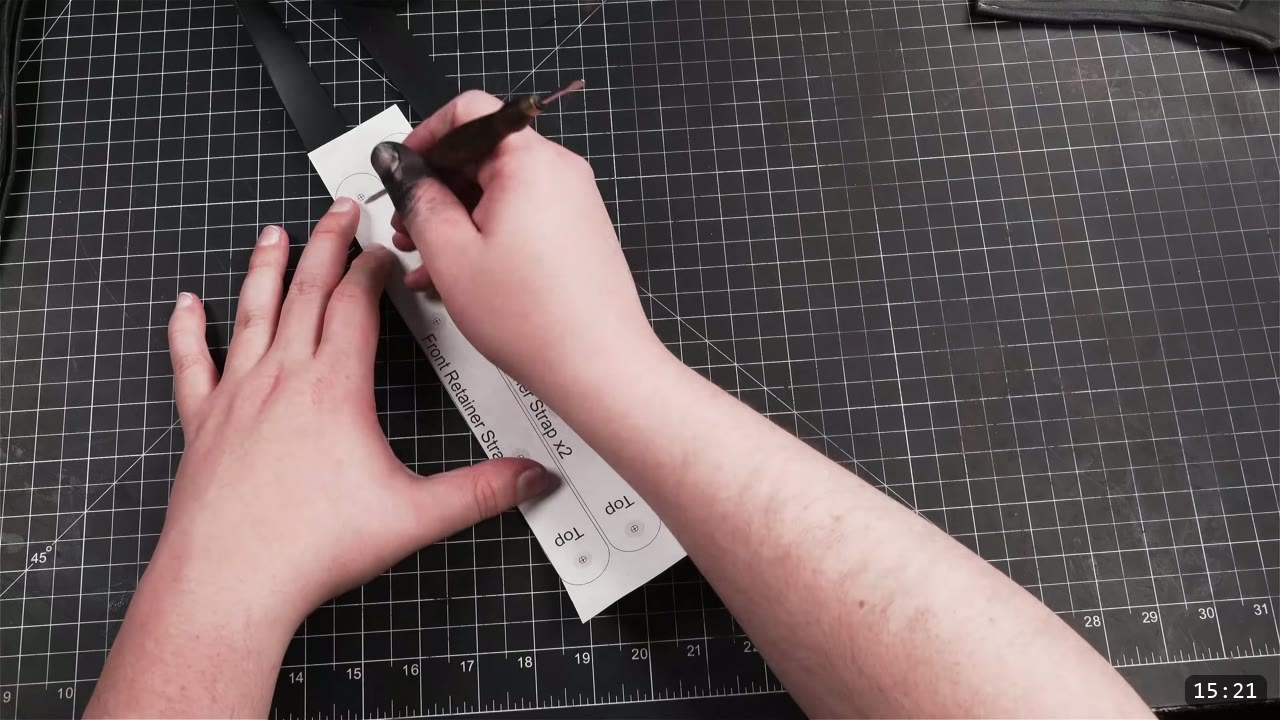 hands marking hole positions with a scratch awl through a white paper pattern labeled Front Retainer Strap and Top, a dark leather strap alongside