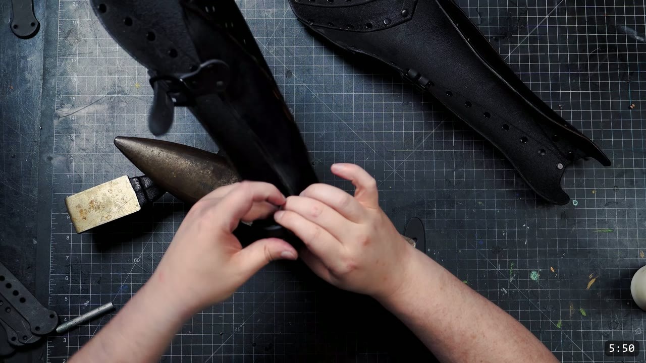 Beginner Leather Greaves Build Guide: The Easy Leg Armor to Start With 13 the finished pair of black leather greaves with buckle straps attached, fastening a strap over a small anvil