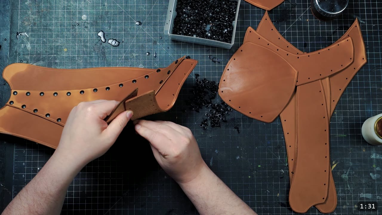 Beginner Leather Greaves Build Guide: The Easy Leg Armor to Start With 4 hands setting black double-cap rivets along the tan greave front, a tray of black rivets and a second greave piece nearby