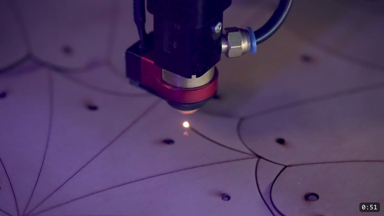 a laser cutter head cutting parts from a sheet of natural vegetable-tan leather marked with the Berserk elbow pattern lines and punched holes