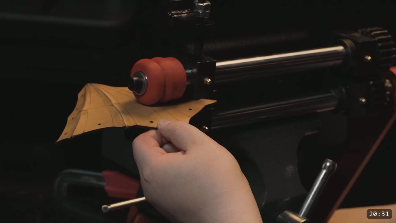 a hand running a natural-tan faceplate piece under a red embossing wheel to raise a fluted line