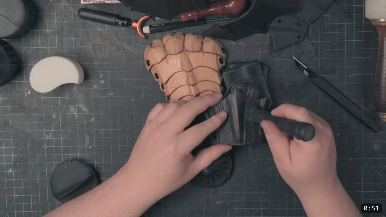 Berserk Gauntlets Build Guide: The Leather Version, Step by Step 2 a natural vegetable-tan gauntlet cuff with fluted scale rows and rivet holes beside a black dyed leather piece being worked by hand on a cutting mat
