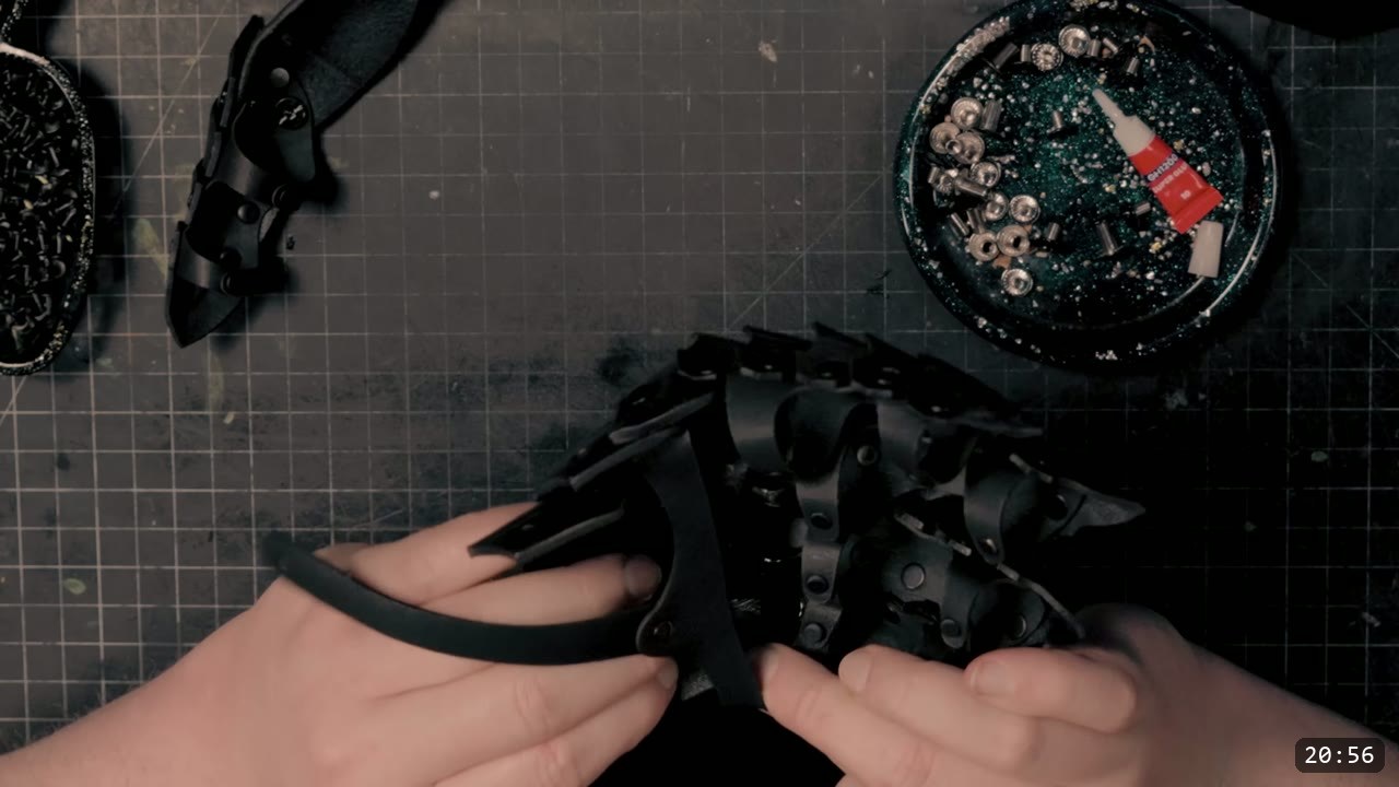 Berserk Gauntlets Build Guide: The Leather Version, Step by Step 16 hands looping a retaining strap onto the assembled black articulated hand plates, a tray of silver Chicago screws and thread lock alongside