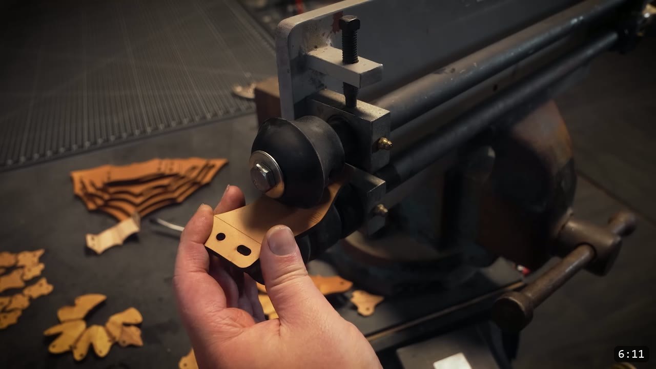 Berserk Gauntlets Build Guide: The Leather Version, Step by Step 7 a tan leather strap fed through a black embossing wheel mounted on a metal bead roller, with laser-cut finger parts on the bench below