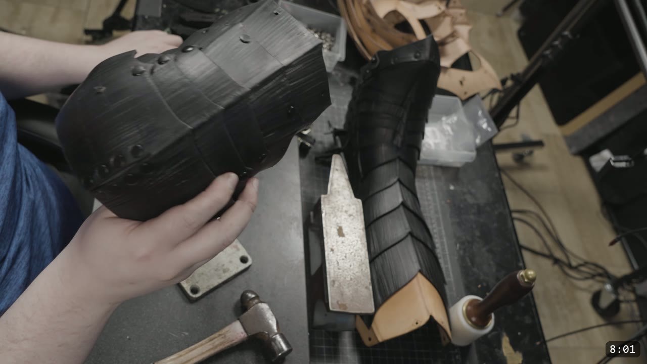 Berserk Greaves Build Guide: Leather Berserker Shin and Calf Armor 13 a hand holding the formed black leather calf section, with a ball-pein hammer and a forming stake on the bench