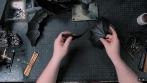 Roadmap Updates & Pre-Order Status 1 overhead view of dyed-black fluted pauldron plates being handled, with a tray of rivets and a wing divider on the bench