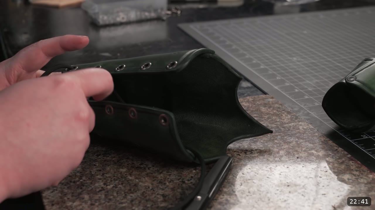 a green bracer opened out showing the row of metal eyelets set along both edges for lacing