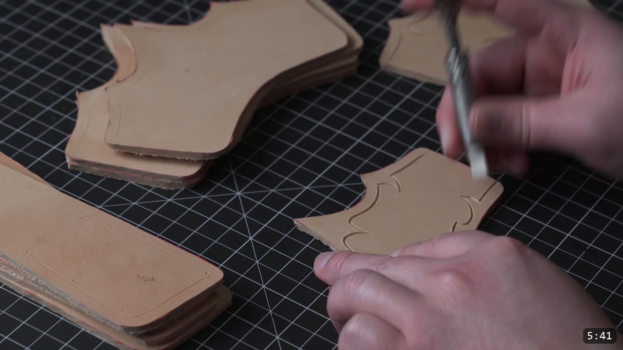 carving the barbed decorative border into a damp leather bracer plate with a swivel knife