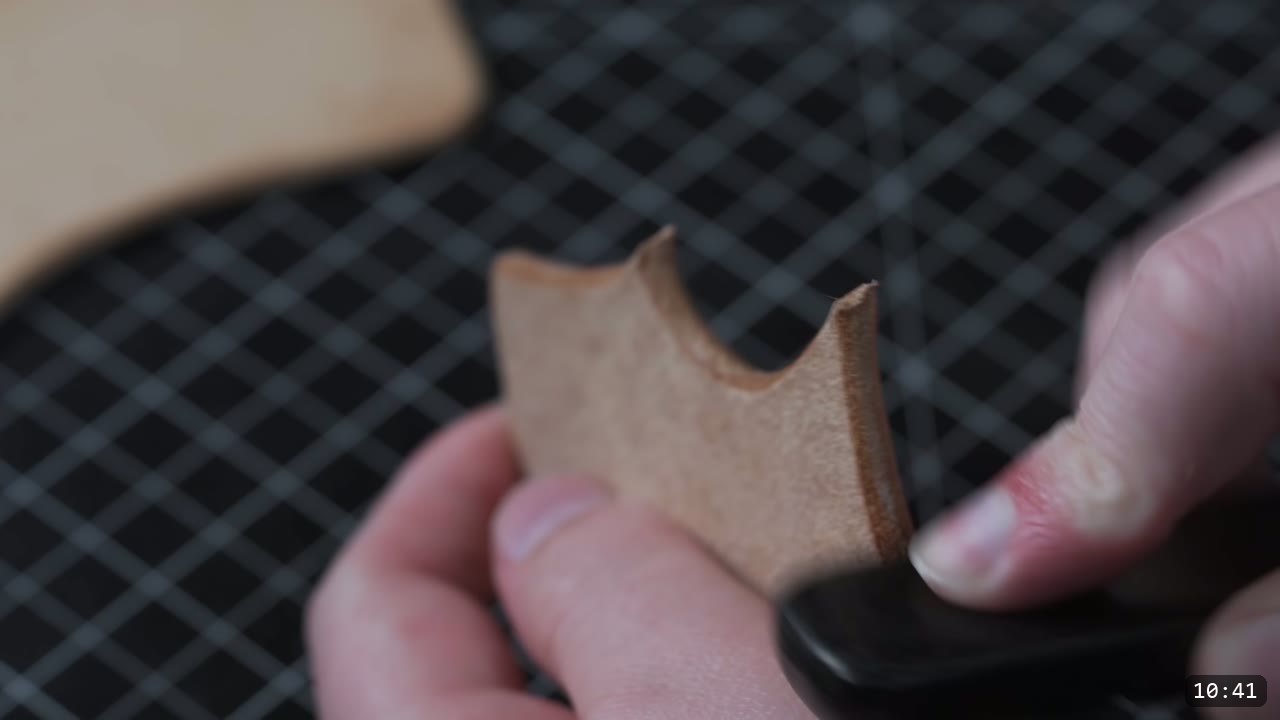 running a burnisher along the edge of a small carved bracer piece to slick it smooth