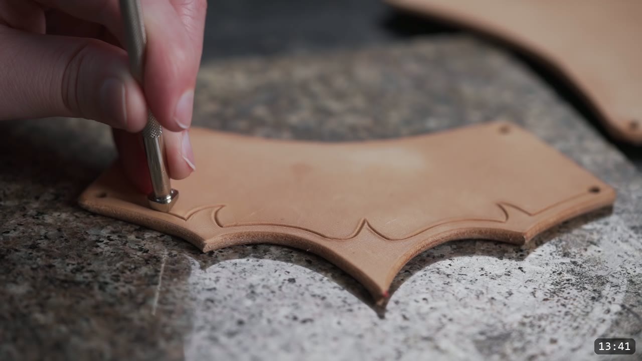 stamping the beveled border along a bracer plate with a metal bevel stamp on a granite slab