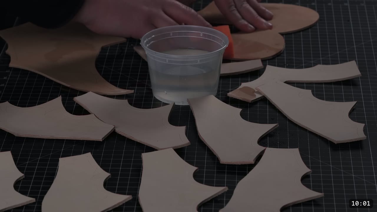 cut fantasy helmet pieces laid out on a black mat around a tub of water and an orange sponge, ready to wet for carving