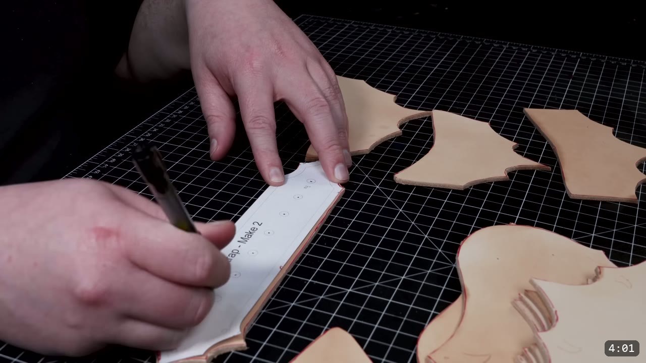 Fantasy Spaulders Build Guide: Leather Shoulder Armor from a Flat Pattern 4 a pen marking a strap pattern piece labeled Make 2 on the mat, with several cut tan leather plates laid out around it