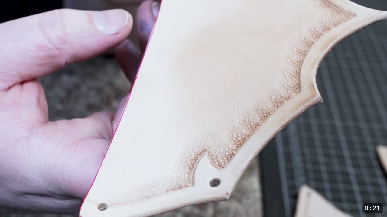 Fantasy Spaulders Build Guide: Leather Shoulder Armor from a Flat Pattern 6 a hand holding a barbed tan plate with a pebble-textured tooled border, a beveled outline, and two punched rivet holes