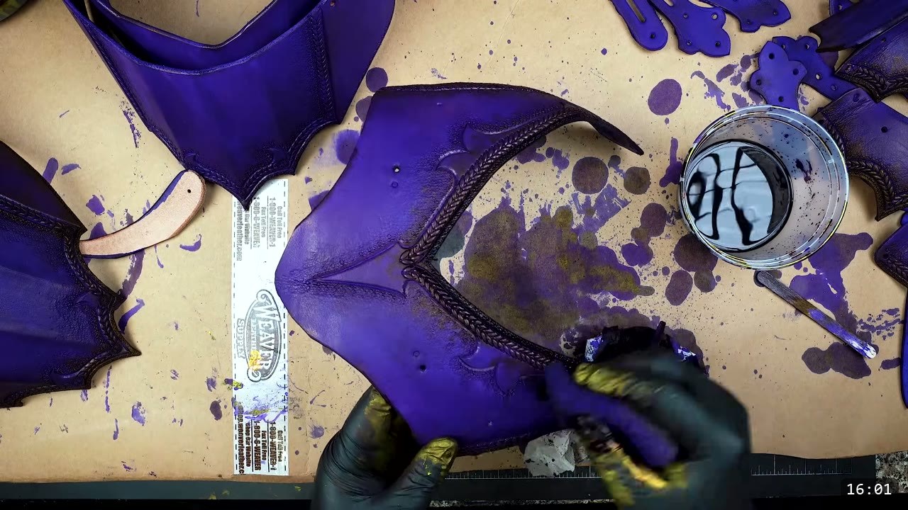 Female Leather Breastplate Build Guide: Articulated Fantasy Armor, Step by Step 11 purple-dyed breastplate pieces with braided tooling on kraft paper, a tin of finish, and gloved hands working a large wing-shaped front piece