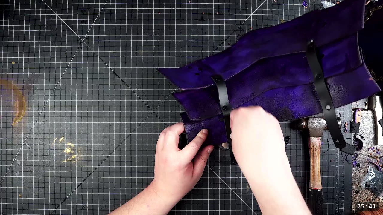 Female Leather Breastplate Build Guide: Articulated Fantasy Armor, Step by Step 15 purple articulated plates joined by two vertical black retaining straps on a cutting mat, with a mallet nearby