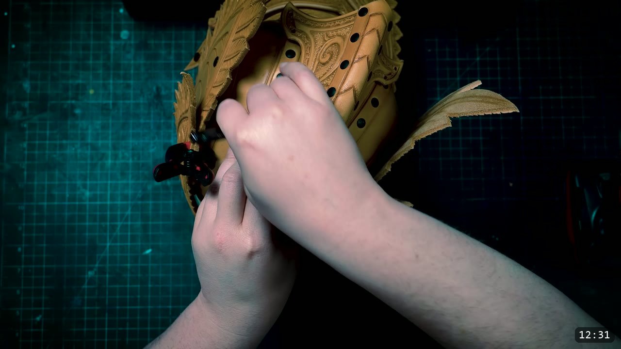 Leather Elven Helmet Build Guide: Visor, Comb, Tail, and a Green Metallic Finish 7 hands riveting a carved feathered comb side plate onto the tooled brow band of the helmet