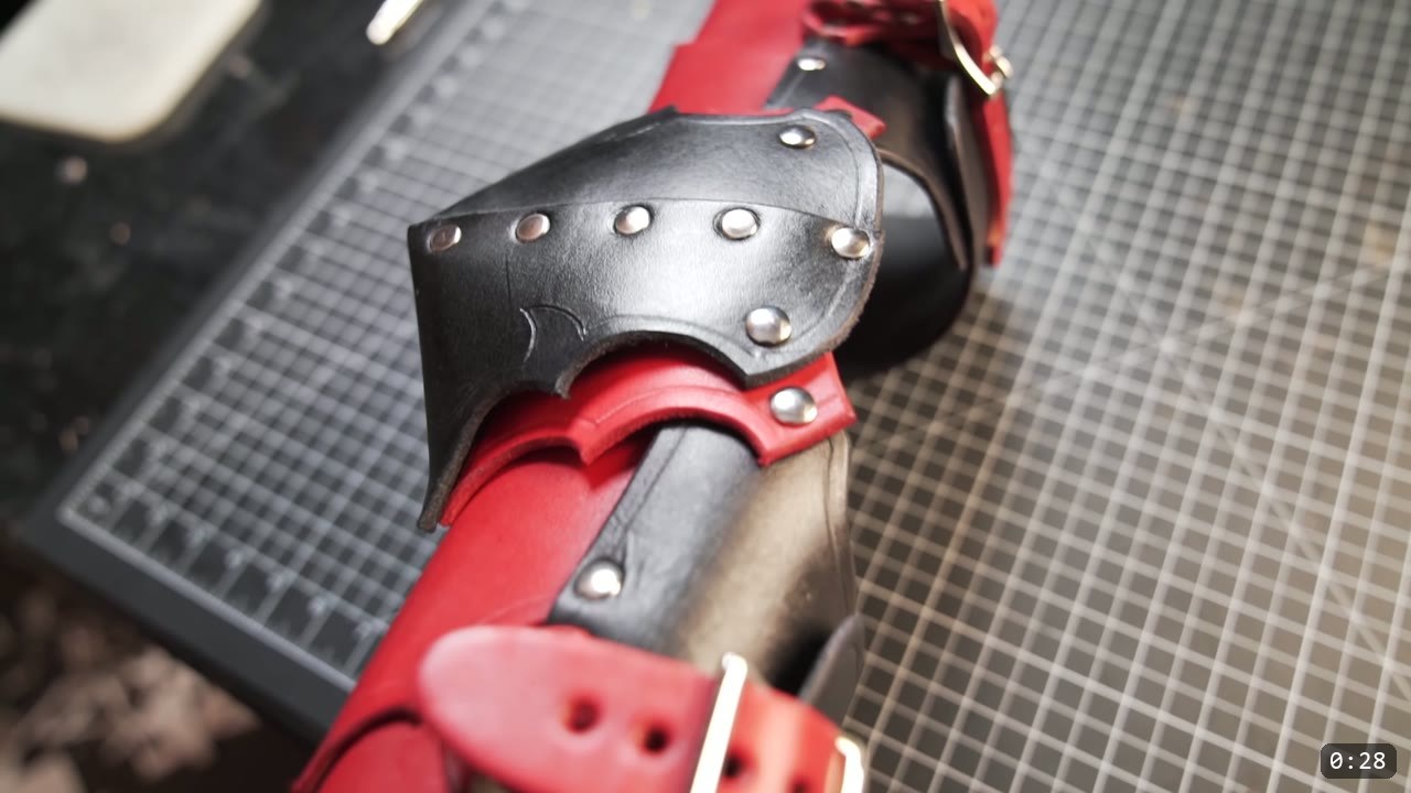 Leather Arm Armor Build Guide: Fantasy Vambrace, Rerebrace, and Elbow 2 finished fantasy leather arm armor detail, a black elbow plate with a barbed lower edge riveted over a red vambrace, silver rivets and a red buckle strap