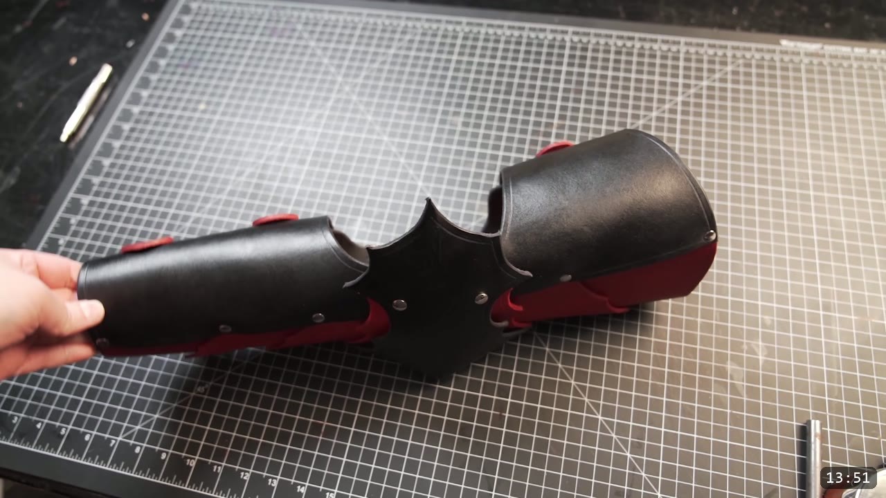 Leather Arm Armor Build Guide: Fantasy Vambrace, Rerebrace, and Elbow 13 the finished fantasy leather arm armor, black plates with red accents and a barbed elbow, held over the cutting mat