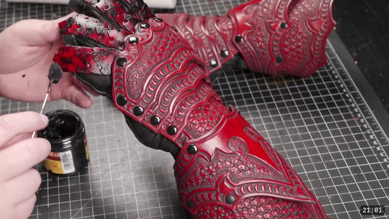 Articulating Leather Gauntlets Build Guide: A Fantasy Set from a Flat Pattern 3 finished red-dyed articulating leather gauntlet with black antiquing worked into the tooling and black rivets, on a black glove