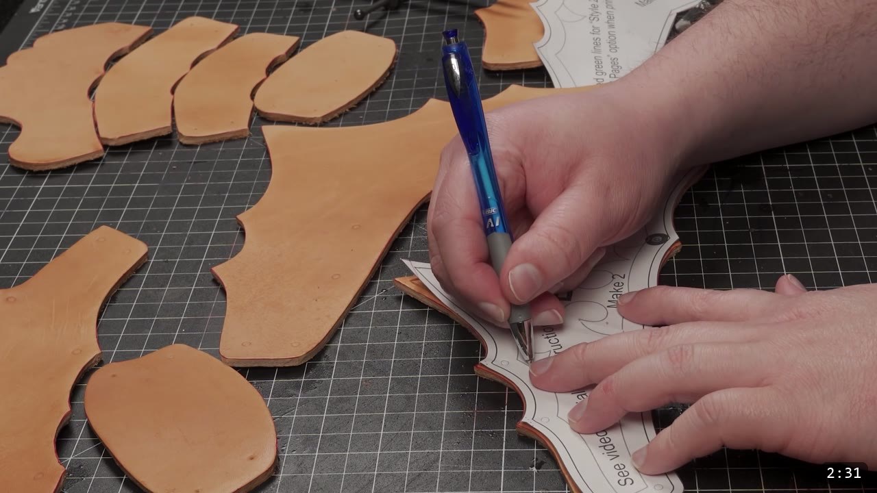 Articulating Leather Gauntlets Build Guide: A Fantasy Set from a Flat Pattern 4 hands tracing design lines over a paper pattern laid on a cut tan leather handpiece with a blue pen on a cutting mat