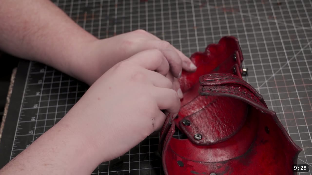 Articulating Leather Gauntlets Build Guide: A Fantasy Set from a Flat Pattern 8 hands adjusting the assembled red leather hand and cuff unit with visible Chicago screws on a cutting mat