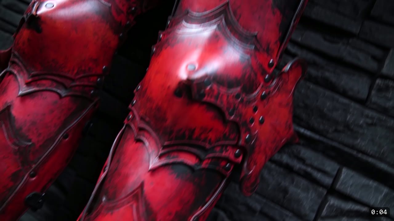 Leather Cuisses and Knees Build Guide: Articulated Upper-Leg Armor 2 a pair of finished red leather cuisses and articulated knees with black weathering, scalloped scale-plate borders, and rivets, standing against a dark stone wall
