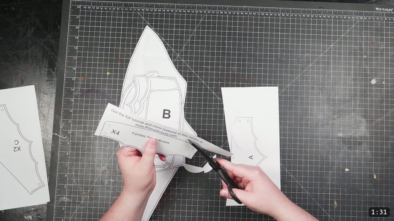 Leather Cuisses and Knees Build Guide: Articulated Upper-Leg Armor 3 cutting out the printed Fantasy Armor knee pattern piece labeled B with scissors on a gridded cutting mat