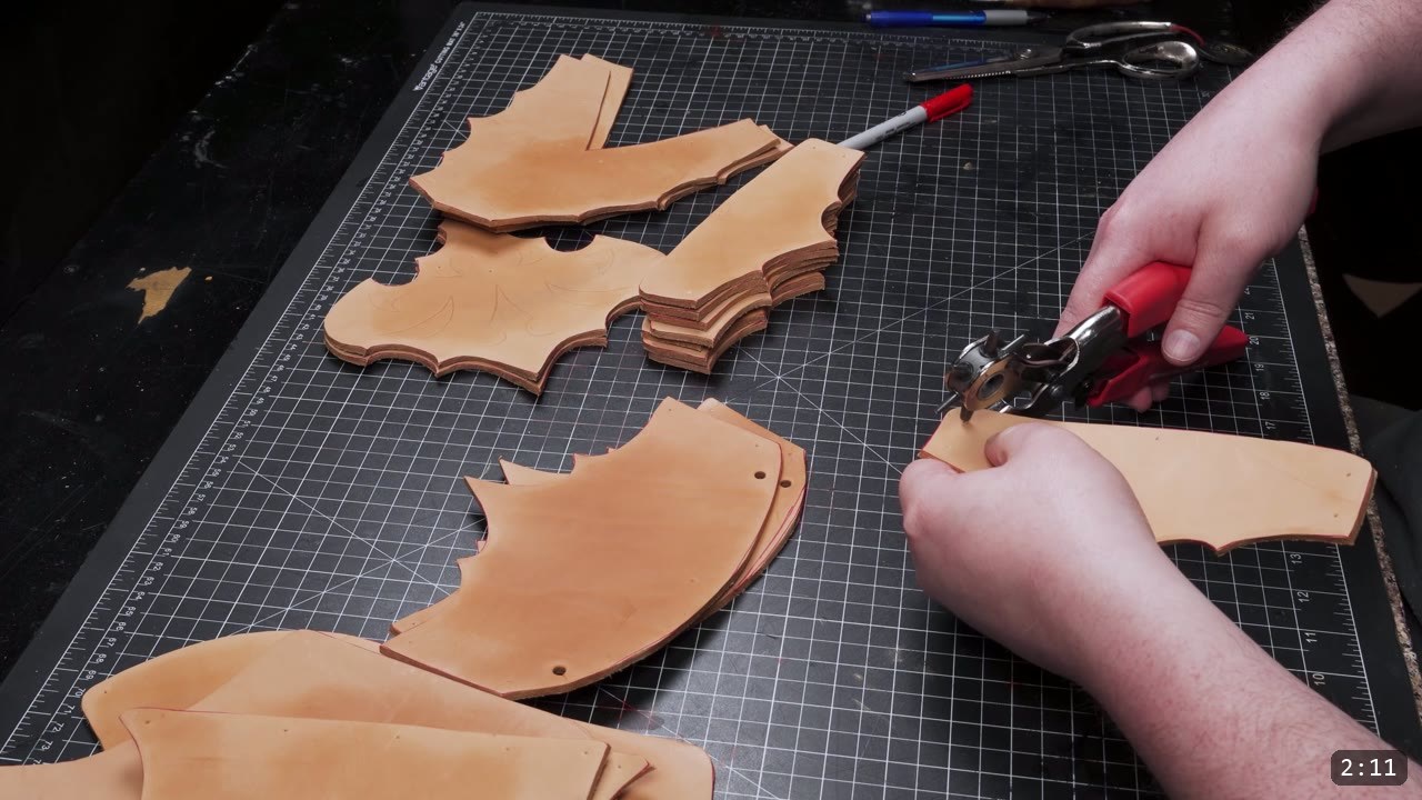 Leather Cuisses and Knees Build Guide: Articulated Upper-Leg Armor 5 punching holes in cut tan leather knee pieces with a red-handled rotary punch, scalloped pieces laid out on the mat