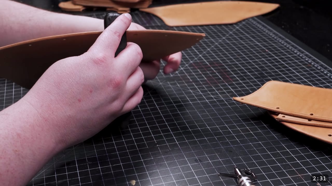 Leather Cuisses and Knees Build Guide: Articulated Upper-Leg Armor 6 working the edge of a cut tan leg piece by hand with an edging tool, stacks of punched pieces nearby