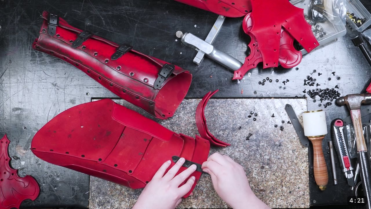 Leather Cuisses and Knees Build Guide: Articulated Upper-Leg Armor 8 red-dyed cuisse, articulated knee lames, and greave laid out with black rivets, Chicago screws, a hammer, and a mallet during assembly