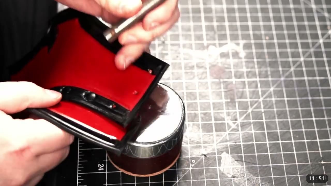 Leather Gorget Build Guide: A Fantasy Armor Neck Guard, Step by Step 12 a steel setter struck over a round metal surface to set hardware on the black-bordered gorget collar piece, rivet holes visible along the edge