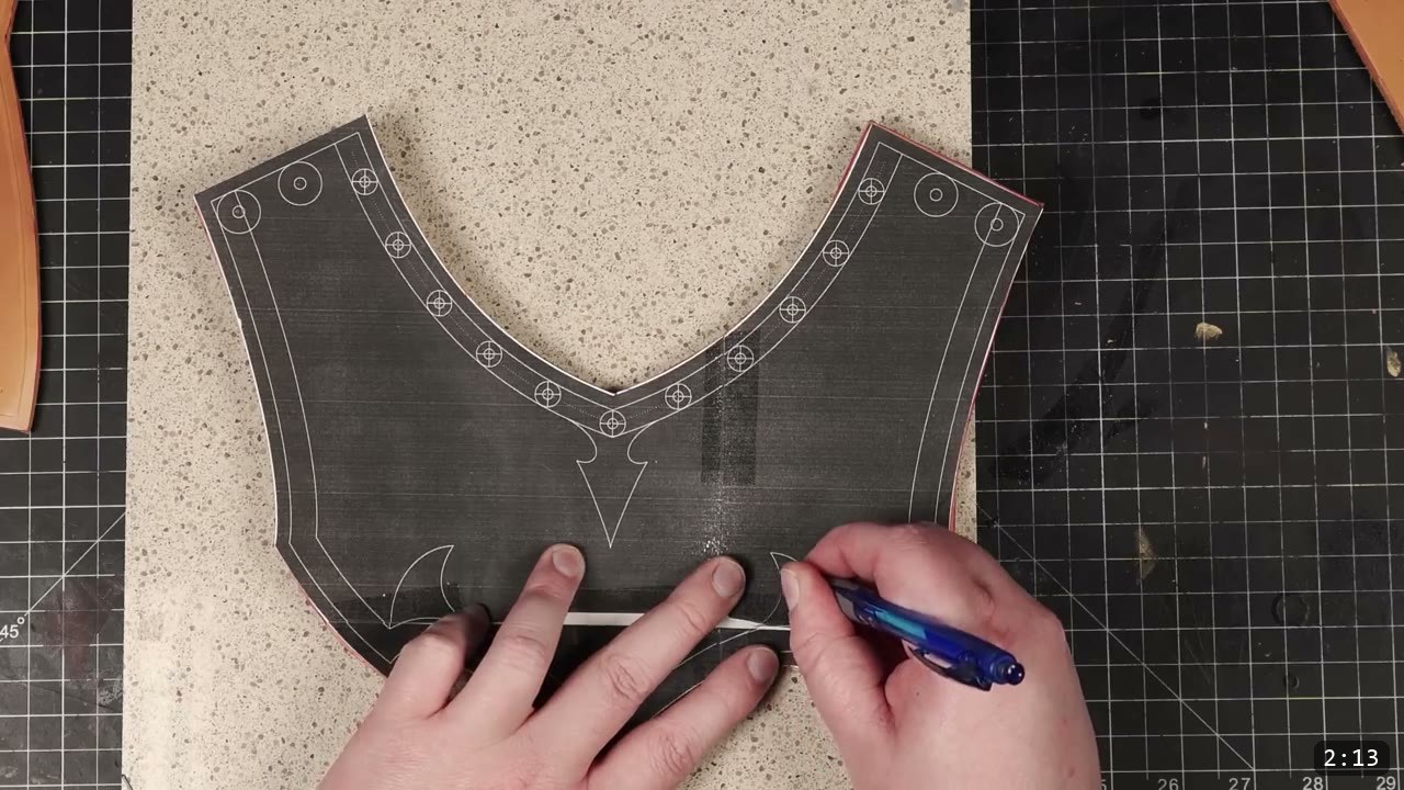 Leather Gorget Build Guide: A Fantasy Armor Neck Guard, Step by Step 6 a blue ballpoint pen tracing the arrow motif and border lines on the gorget front pattern over a stone slab