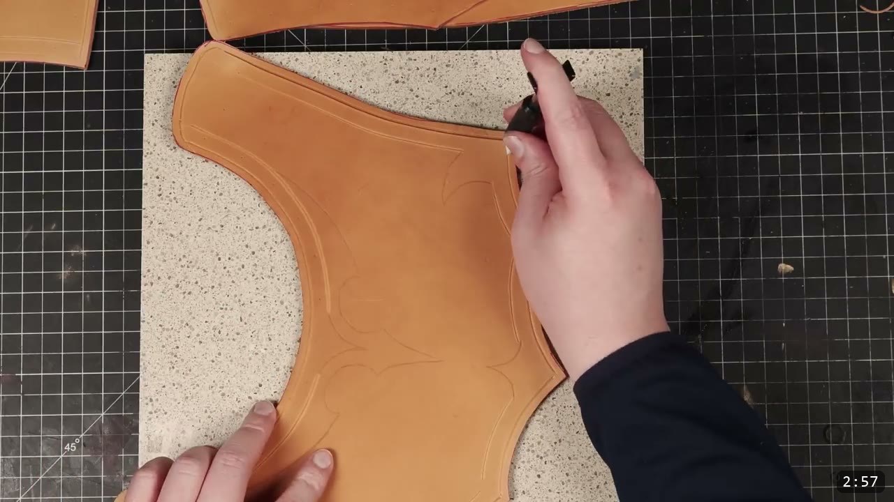 Leather Gorget Build Guide: A Fantasy Armor Neck Guard, Step by Step 7 a swivel knife carving the decorative border lines into a cut tan gorget front piece on a granite slab