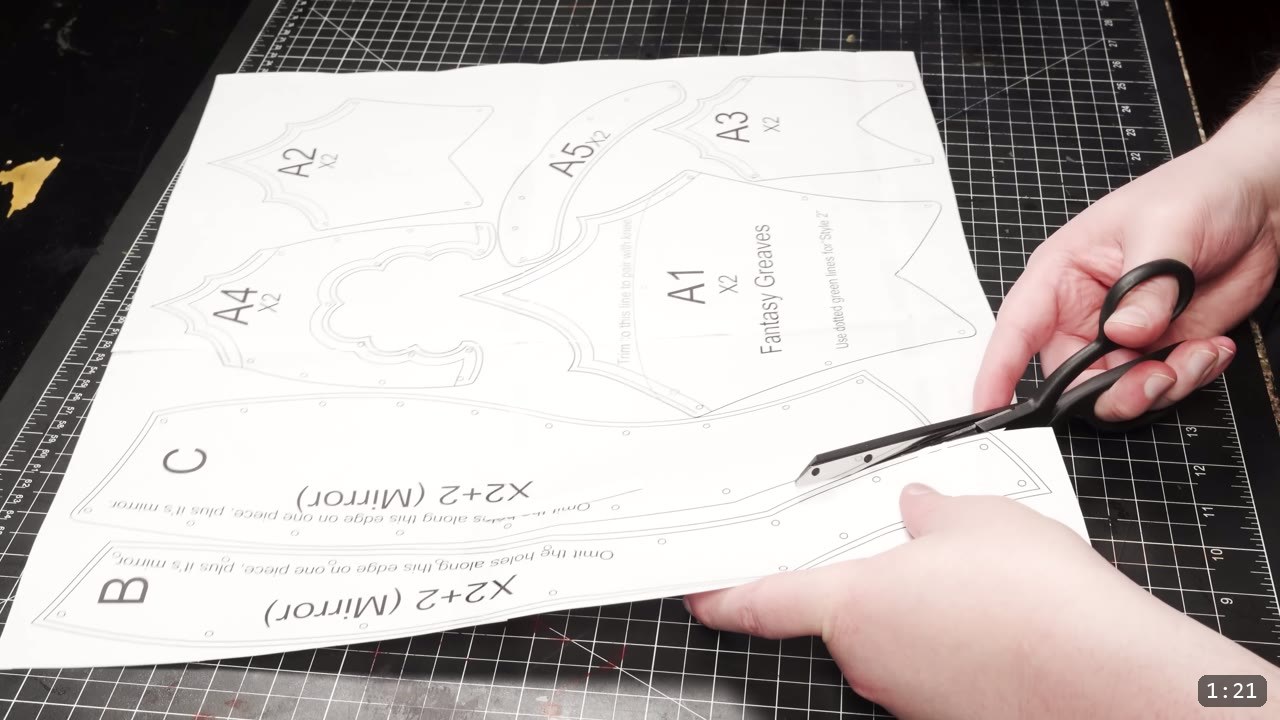 Leather Greaves Build Guide: From Flat Pattern to Antiqued Leg Armor 2 printed Fantasy Greaves pattern pieces on a black cutting mat, labeled A1 through A5 with mirrored B and C panels, trimmed with scissors