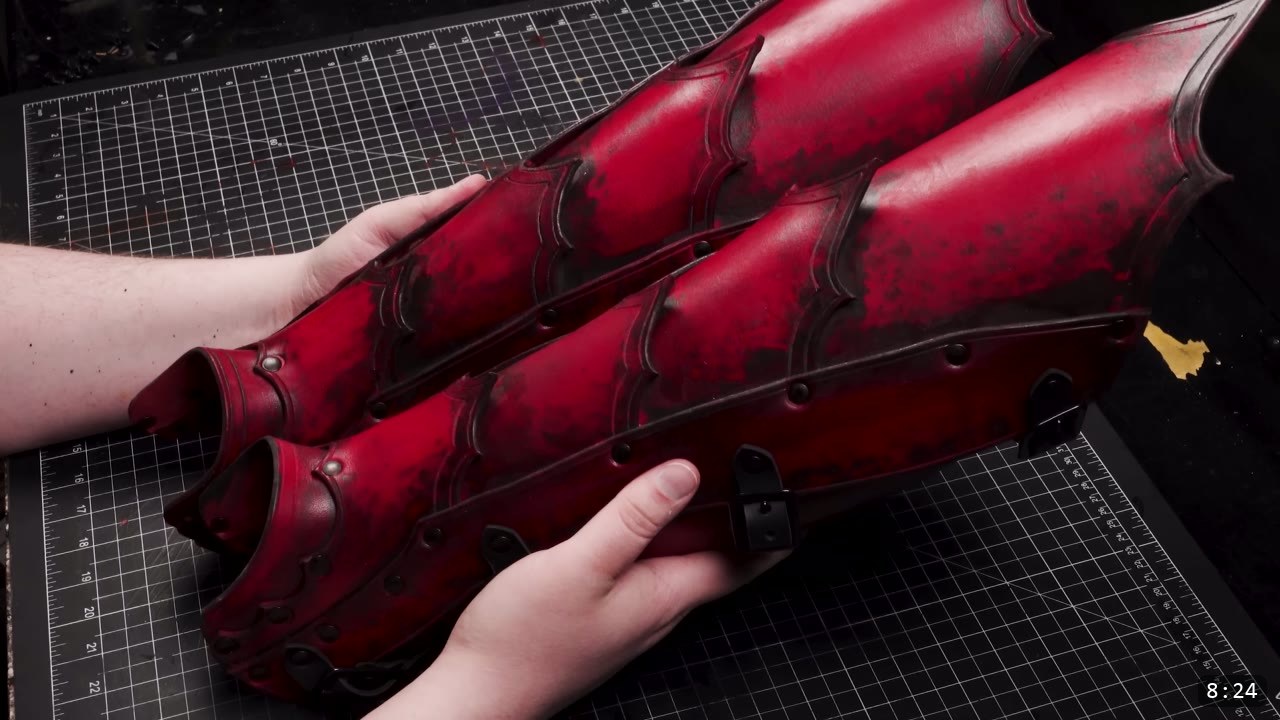 Leather Greaves Build Guide: From Flat Pattern to Antiqued Leg Armor 3 a finished pair of red leather greaves with black antiquing worked into the recesses, scalloped tooled borders, dome rivets, and black buckles
