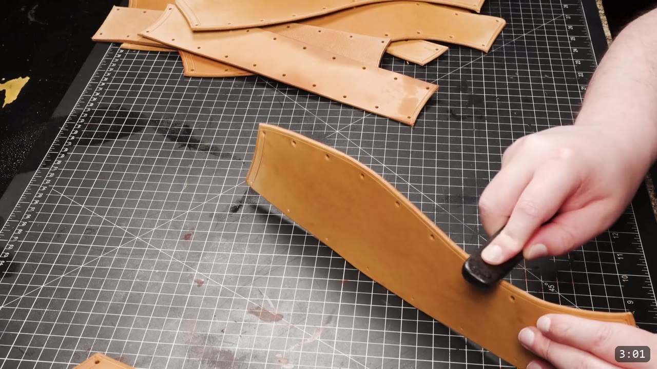Leather Greaves Build Guide: From Flat Pattern to Antiqued Leg Armor 6 burnishing the edge of a cut greave panel with a slicker, other panels showing a punched rivet-hole row and a double-channel border groove