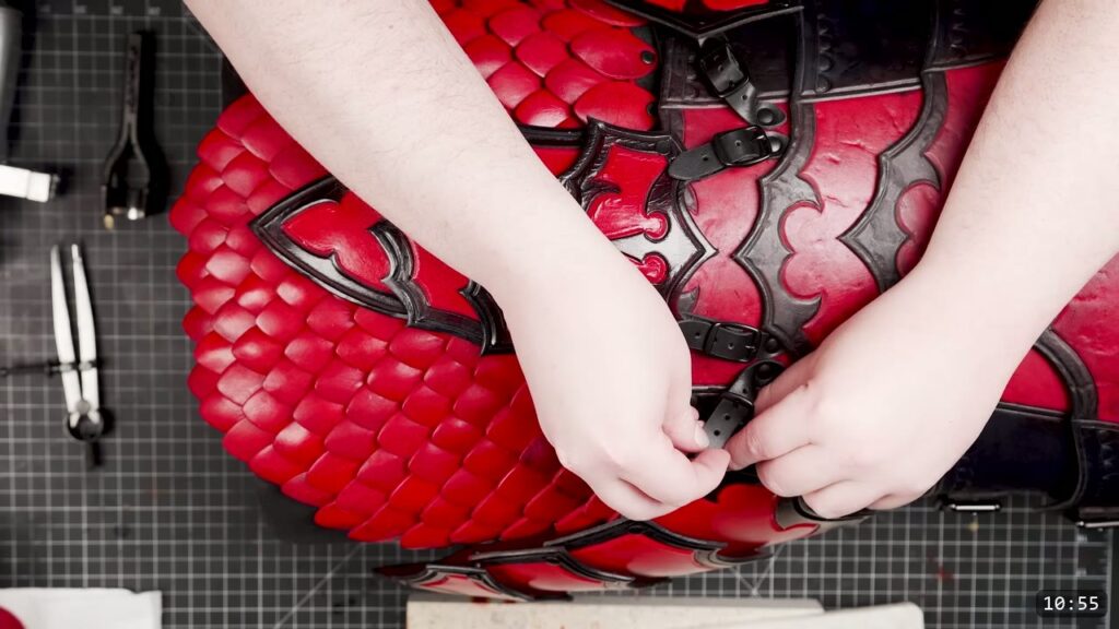 the finished red leather scale skirt buckled onto a red and black fantasy breastplate with black buckle straps