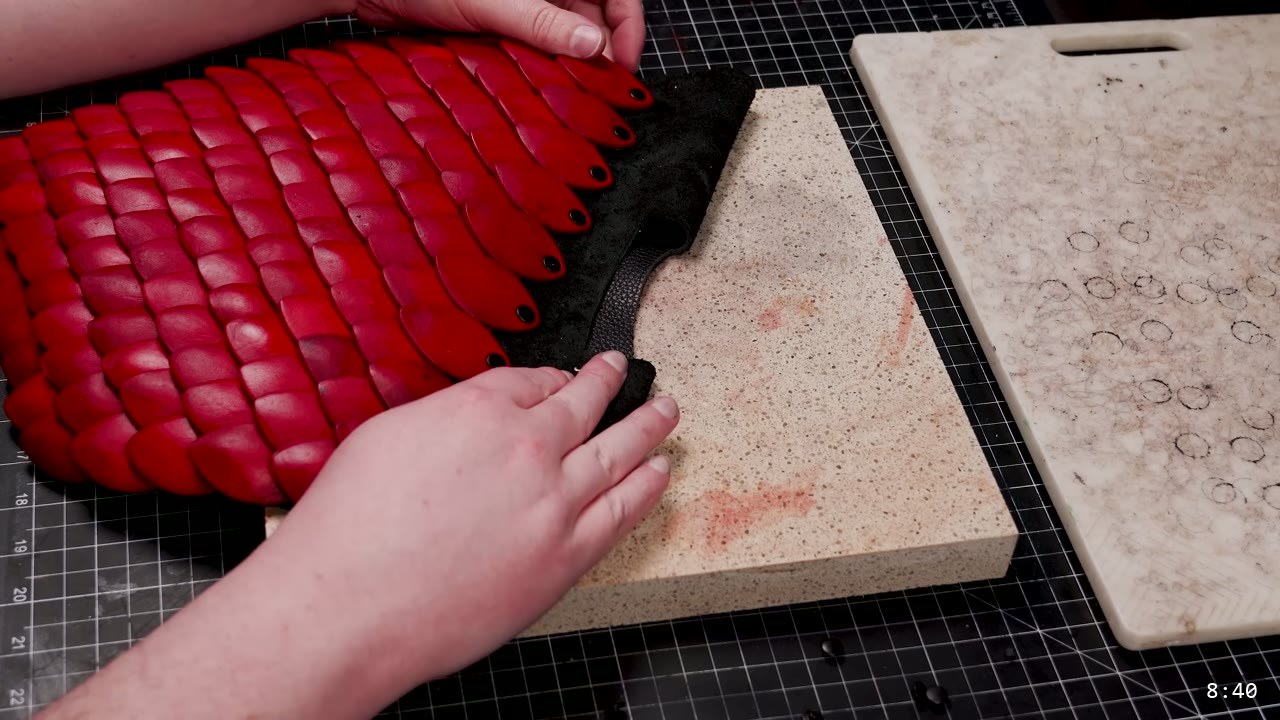 Leather Scale Armor Build Guide: A Flexible Scale Skirt from Scrap Leather 10 rows of glossy red dyed leather scales riveted in overlapping courses across the black backing panel on a stone slab