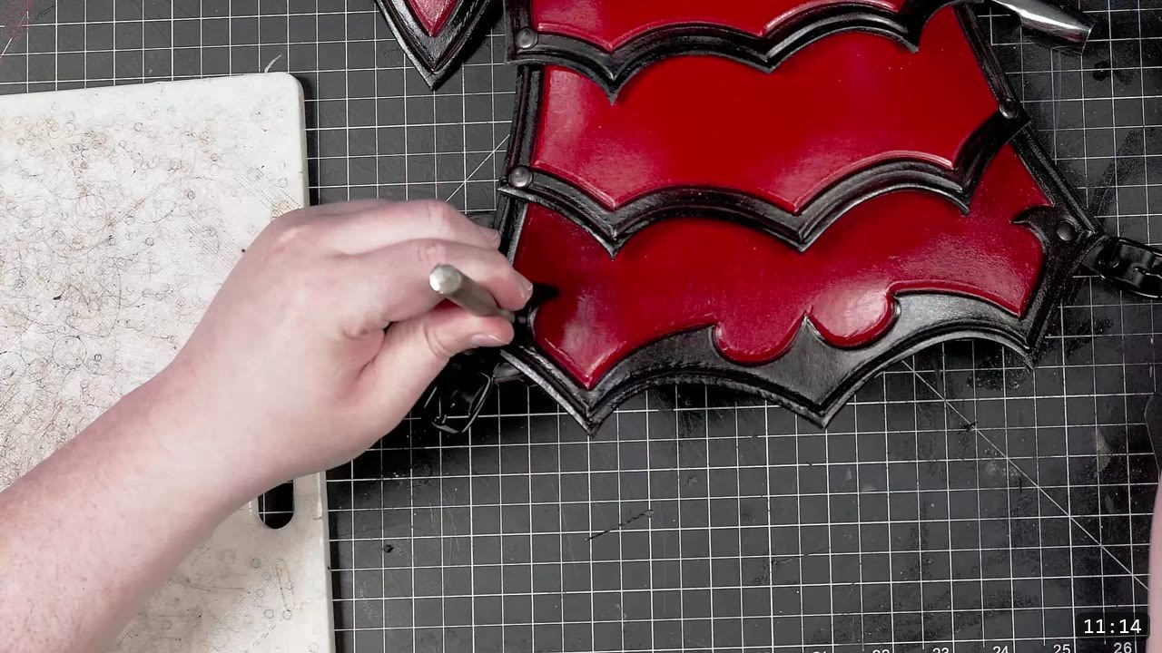 Leather Tassets Build Guide: Fantasy Armor Tassets from a Flat Pattern 12 marking a strap position on a finished red and black tasset with a stylus on a cutting mat