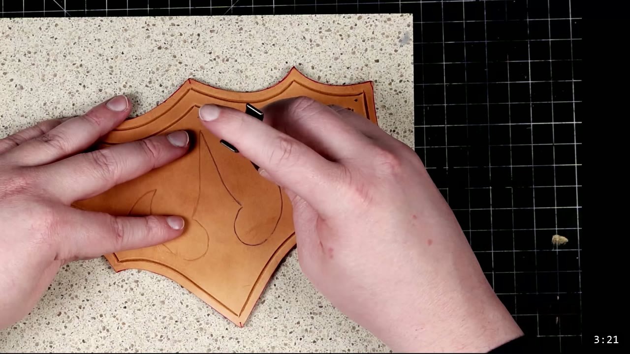 Leather Tassets Build Guide: Fantasy Armor Tassets from a Flat Pattern 4 carving a border line into a cut tan tasset with a swivel knife on a stone slab, a flame motif marked in the center