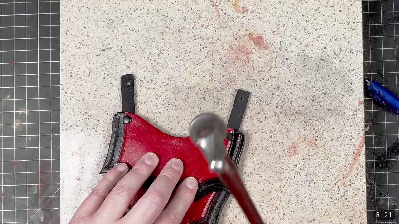 Leather Tassets Build Guide: Fantasy Armor Tassets from a Flat Pattern 10 setting a double-cap rivet on a red tasset strap with a domed setter and mallet on a stone slab