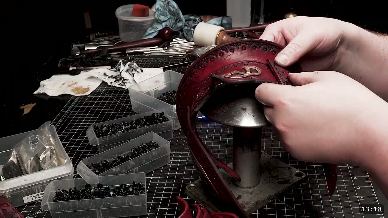 Fantasy Spaulders, Full Suit Version: Leather Shoulders That Mount to the Breastplate 11 hands fitting a gold-tooled deep-red spaulder dome over the steel mushroom stake, black rivets and screws sorted in trays alongside