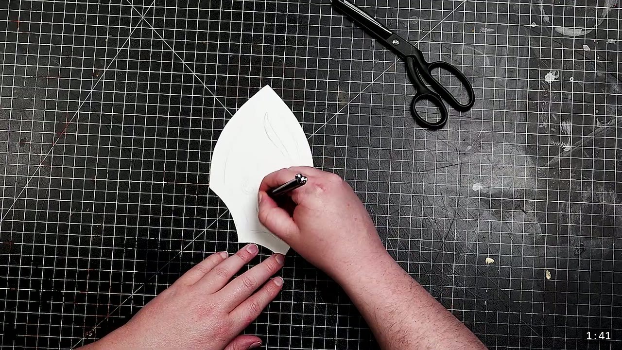 Fantasy Spaulders, Full Suit Version: Leather Shoulders That Mount to the Breastplate 3 a stylus marking a pointed paper spaulder pattern piece on a gridded cutting mat with black shears resting above it