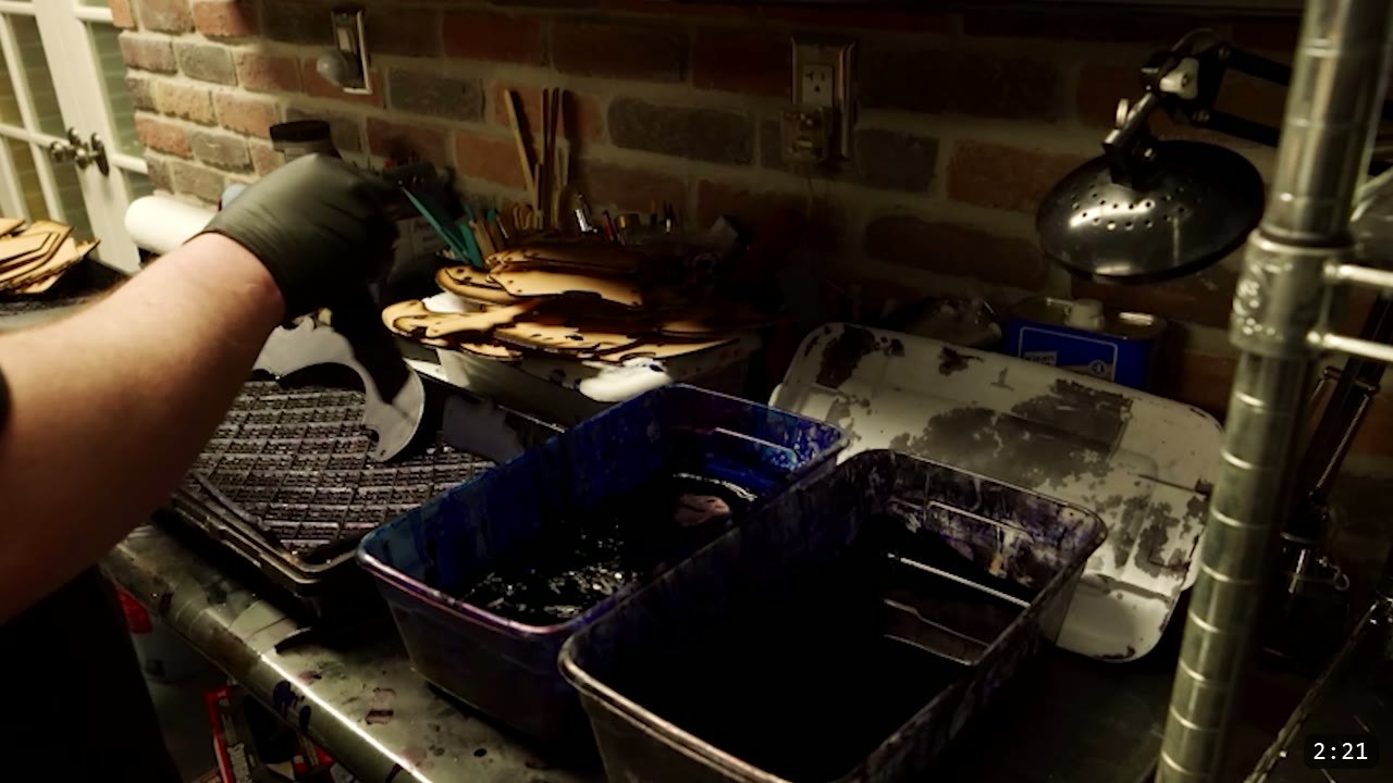 Articulated Leather Arm Armor Build Guide: The Imperial Knight Arms 4 a black-gloved hand lifting leather pieces beside dark dye dip-bins in the workshop, with a drying rack of dyed pieces behind