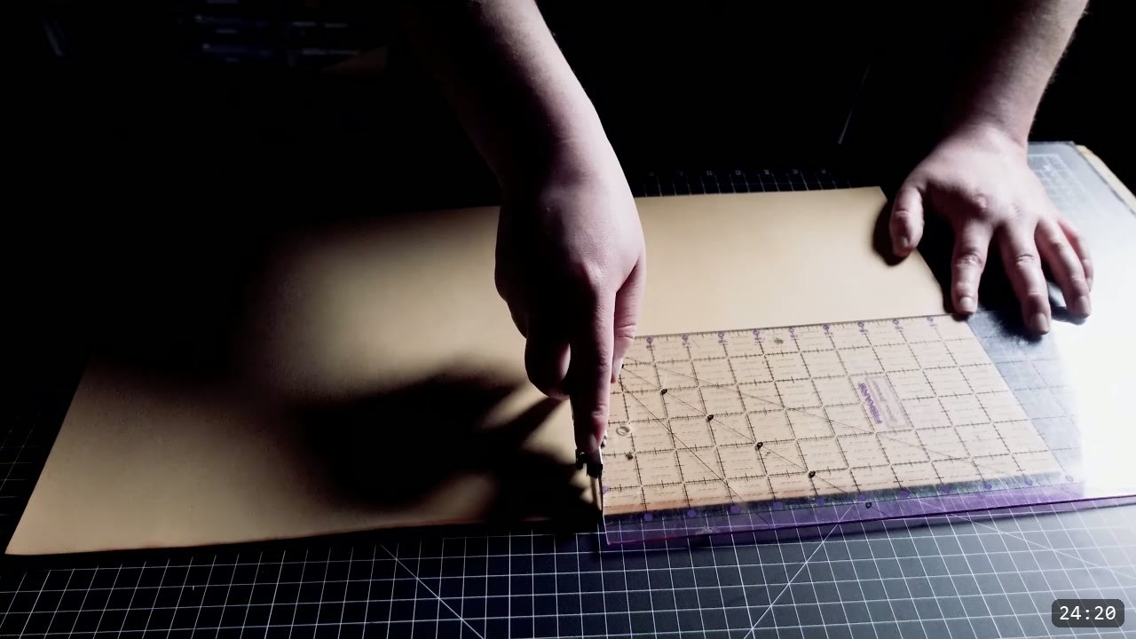 cutting a vegetable-tan buckle strap against a clear quilting ruler on a cutting mat