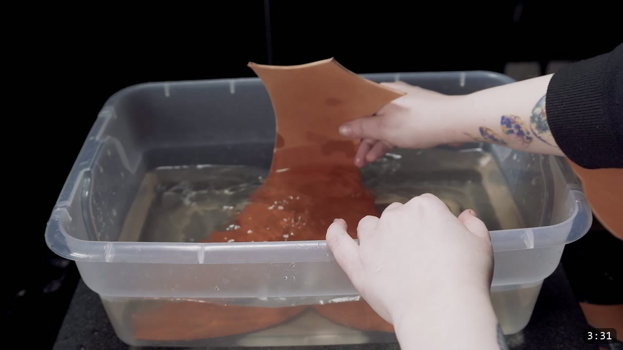 dunking a cut vegetable-tan corset piece into a tub of water to soften it