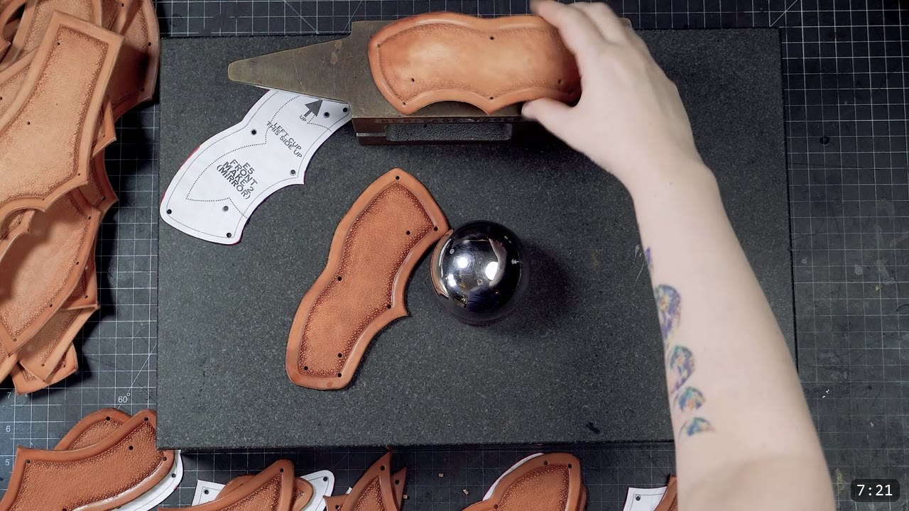 stretching a damp corset piece over a polished steel ball to form a shallow dome, other shaped pieces and a labeled pattern nearby