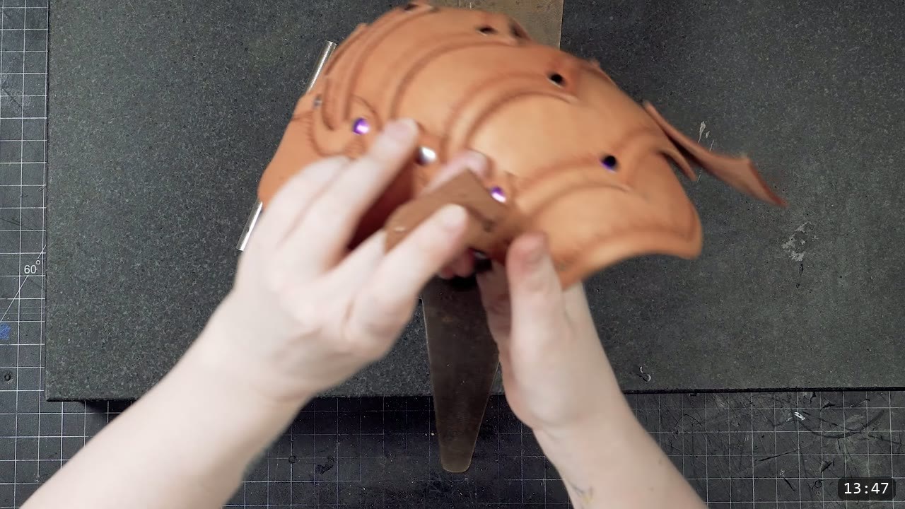 pressing overlapping riveted cup sections together over a pointed steel stake to force the flat leather into a curved shape