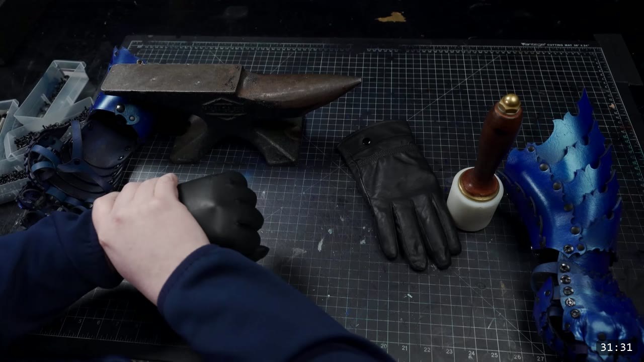 Articulating Leather Gauntlets Build Guide: Imperial Knight, Cut to Finish 12 a horned anvil with a plain black leather glove laid flat on the mat, a gloved fist at left beside a blue cuff, and another blue gauntlet at the right