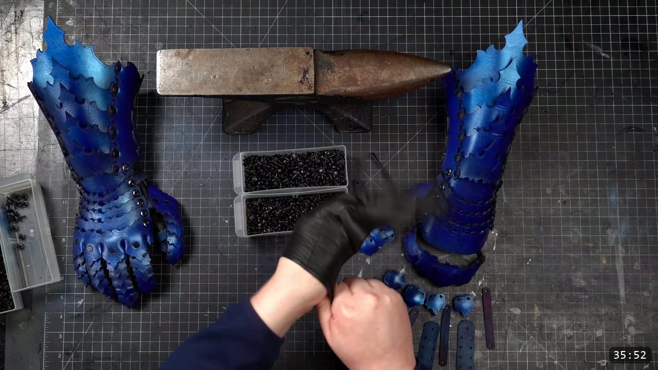 Articulating Leather Gauntlets Build Guide: Imperial Knight, Cut to Finish 13 both finished blue articulating leather gauntlets standing upright with full jointed finger scales, a horned anvil and two trays of black rivets between them